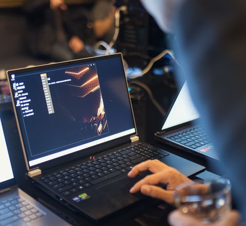 A laptop running a dark security console on a desk beside a second machine