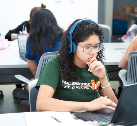 A student working through course material on a laptop in a classroom